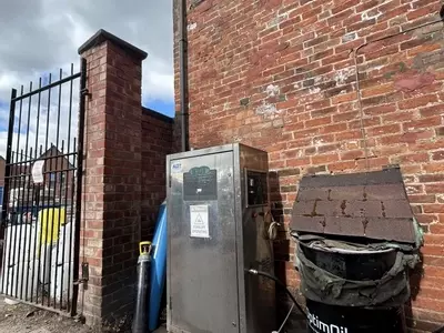 Nilfisk DTE static pressure washer in a brewery courtyard in Burton prior to flue extension installation, where boiler exhaust fumes were building up in the confined wash area during high-temperature keg cleaning.